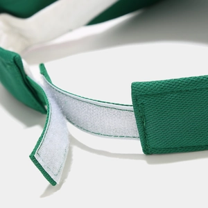 Détail de la sangle velcro blanche réglable sur une casquette visière verte aérée