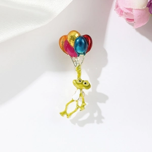 Détail d'une broche grenouille en émail avec ballons colorés et finition métallique