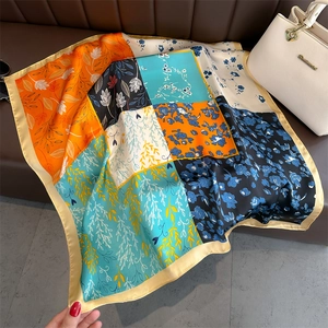 Foulard en soie florale avec imprimés botaniques orange et bleu sur un canapé foncé