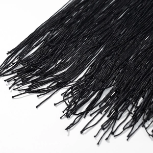 Détail en gros plan de franges à pompons noirs avec texture de corde tressée dense