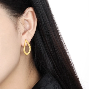 Elegant gold drop-shaped hollow earrings with brushed texture for women on model