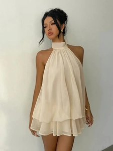 Detail of the pleated halter neckline and layered chiffon fabric on a beige mini dress