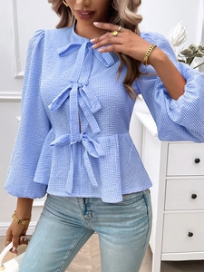 Detail of blue plaid long sleeve shirt featuring puff sleeves and three front bow ties