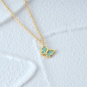 Detail of gold butterfly pendant featuring turquoise blue inlay on S925 silver chain