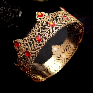 Detailed view of luxury gold baroque crown featuring red gemstones and intricate metalwork