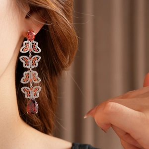 Gros plan de boucles d'oreilles papillon vintage avec strass rouges et longues franges