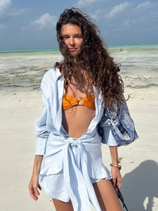 Linen light blue tie-waist shirt dress styled with orange bikini on a sunny beach