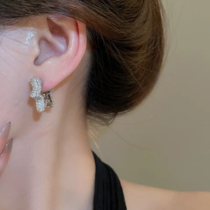 Close-up of sparkling silver hoop earring with pavé zircon stones worn on the earlobe
