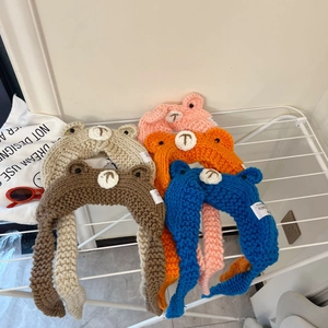Knitted baby bear earflap hats in five colors including beige and pink on white hangers