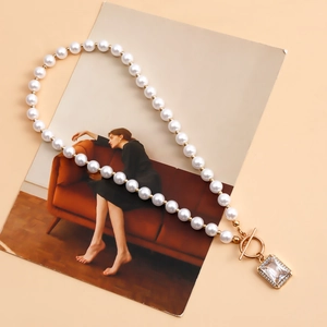 Detail of faux pearl necklace with golden OT buckle and crystal rectangle pendant