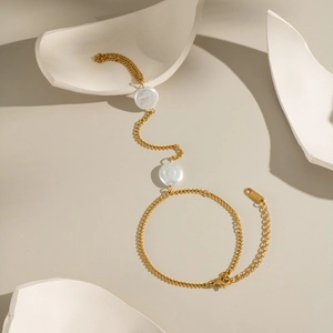 18K gold plated stainless steel finger chain with white pearls on a minimalist background