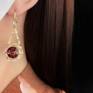 Close-up of French luxury earrings with round red crystal and zircon inlays on model