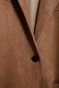 Detail view of premium brown suede fabric texture and a black round button on the collar