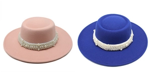 Close-up of wool felt flat top hats in pink and royal blue with elegant pearl bands