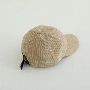 Vue détaillée de la texture du velours côtelé beige et des coutures de la casquette enfant
