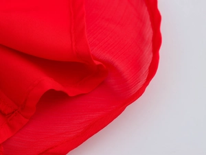 Macro detail of the red fabric showing fine texture and professional hem stitching
