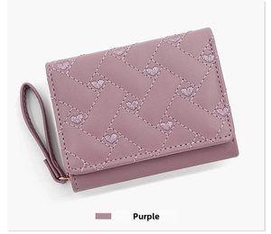 Detail view of purple tri-fold wallet featuring woven texture and heart embroidery