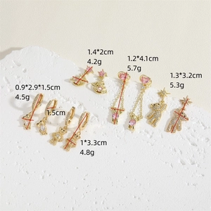 Golden bear and Saturn earrings with pink zircon and stars displayed with dimensions