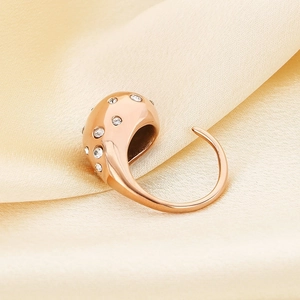Close-up of rose gold water drop ring with sparkling crystals on champagne silk background