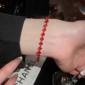 Close-up of 18k gold bracelet with square-cut red gemstones on a female wrist