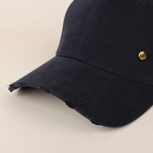 Detail of distressed brim and golden H logo on navy cotton baseball cap with macro focus