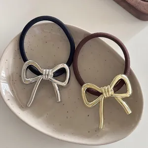 Close-up of elegant bow hair ties in gold and silver finish on a ceramic tray