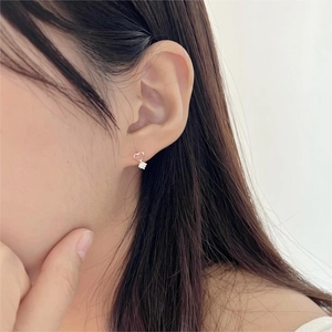 Close-up of minimalist silver heart earring with dangling zircon stone on a model