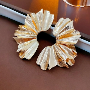 Detailed view of golden leaf-shaped fan pleated earrings with metallic petal texture