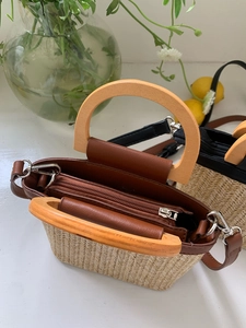Detail view of woven mini bucket bag featuring a wooden handle and secure zipper closure