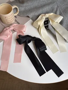 Détail de nœuds à cheveux en satin rose, noir et beige avec de longs rubans sur une table
