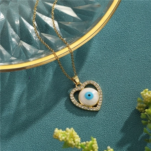 Golden heart necklace with evil eye pendant and zircon inlay on a decorative glass tray