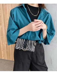 Detail of zebra print waist bag with gold ring hardware on a green shirt model