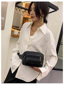 Détail du sac banane noir motif crocodile avec fermetures éclair argentées sur le torse