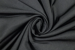 Detail shot of black knitted fabric with fine diagonal textures and elastic drape