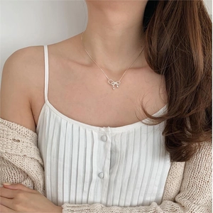 Close-up of elegant silver bow pendant necklace worn by a model on the collarbone