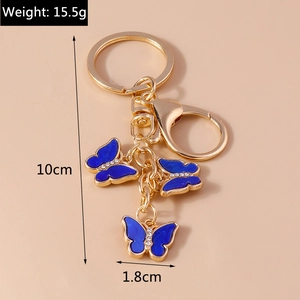 Detailed view of gold butterfly keychain with blue enamel inlay and sparkling crystals