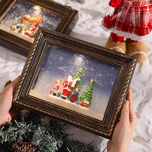 Handheld vintage gold Christmas frame with warm lighting and Santa Claus scenery