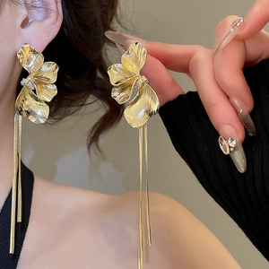 Vue macro des boucles d'oreilles fleur dorée avec de longues chaînes à pompons