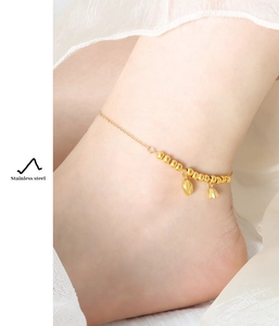 Detailed close-up of a gold stainless steel anklet with heart and bell pendants