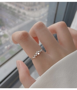 Primo piano di un delicato anello aperto in argento sterling con stelle scintillanti sul dito