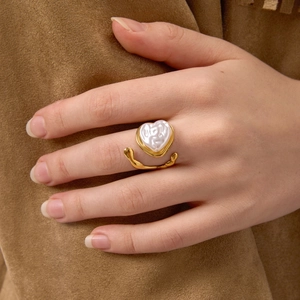 Gros plan d'une bague perle en forme de cœur avec métal doré fluide sur daim chaud