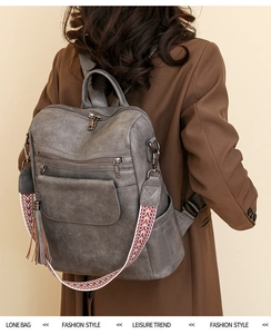 Detail of grey PU leather backpack with colorful geometric strap and tassel on model