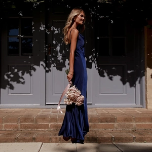 Détail d'une robe longue en satin bleu foncé avec col en V et dos nu élégant