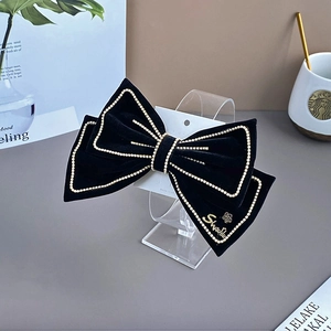Detailed view of luxury black velvet bow hair clip with sparkling rhinestone edges