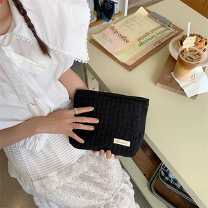 Detail of black seersucker cosmetic bag with Sozakka label in a cozy cafe setting
