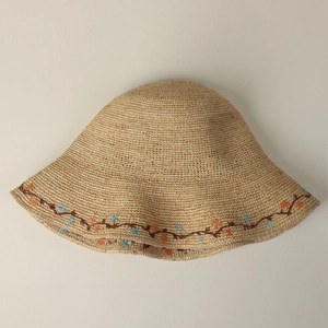 Detailed view of hand-woven raffia sun hat featuring intricate floral embroidery on brim