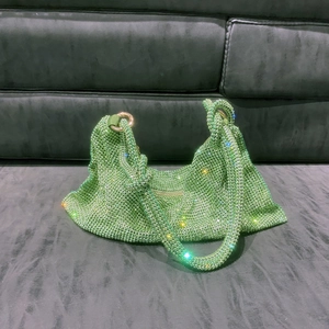 Detailed macro view of the knotted handle and green rhinestones on the luxury hobo bag