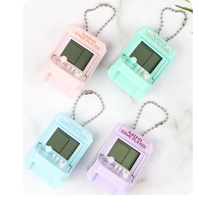 Miniature retro game player keychains in pastel colors on a white marble surface