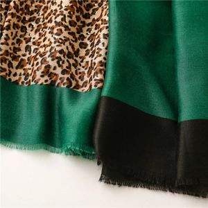 Detailed close-up of leopard print scarf with dark green panels and fringe edges
