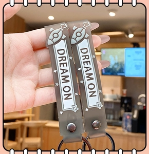 Detail of grey silicone key ring straps featuring Dream On text and rocket graphics